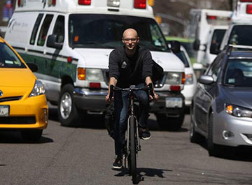 Student riding bike on city streets