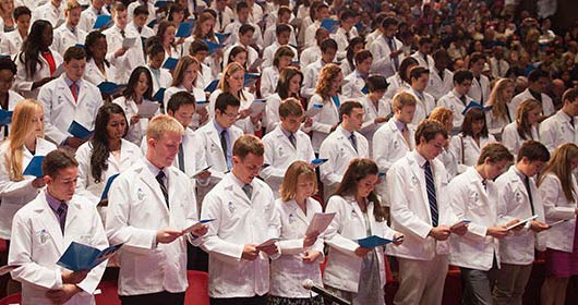 Students standing during white coat ceremony